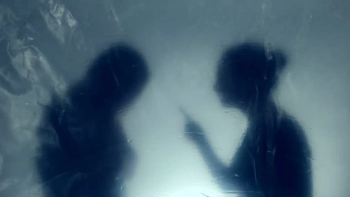 Two silhouettes behind frosted glass in the short film Betrayal, minimalist piano score by Santiago Bianchi